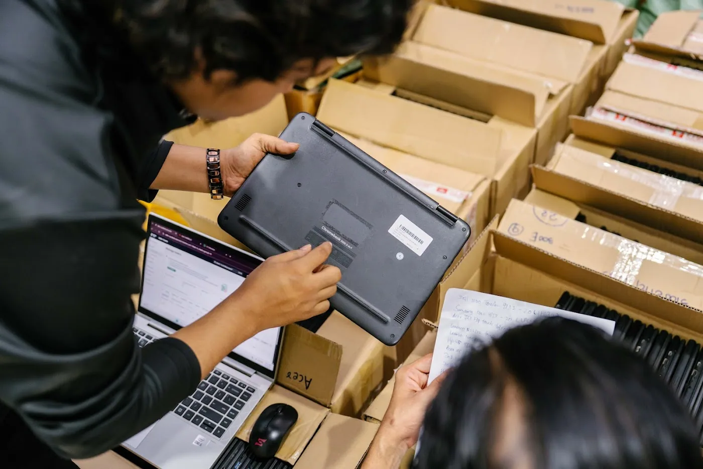 An SCE technician inspecting and logging each incoming laptop against its intake record