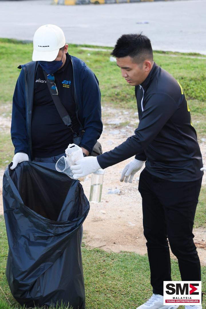 Two volunteers in gloves collecting litter into a bag during an SCE community clean-up