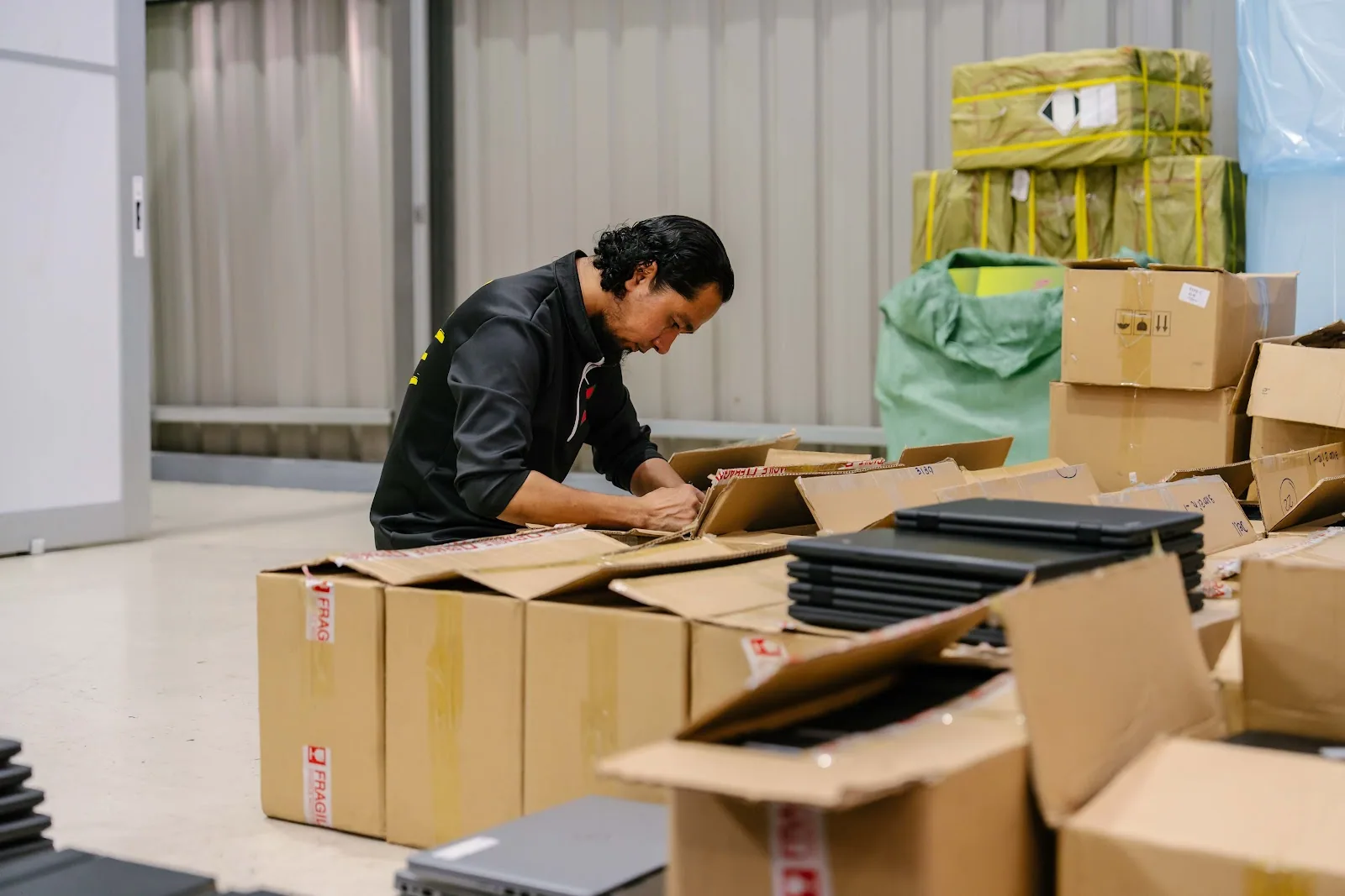 An SCE technician labelling cartons of refurbished laptops packed for a fleet delivery